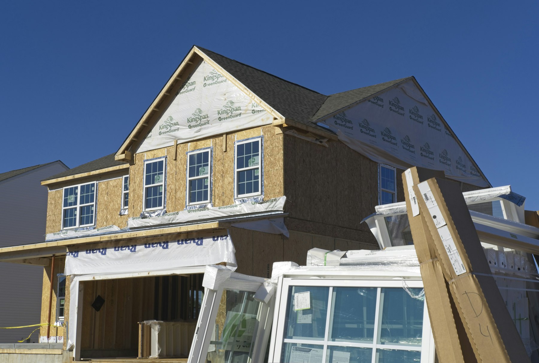 Windows staged beside a house under construction
